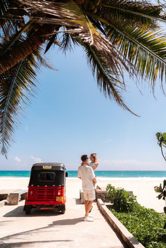 A couple hugging each other and tuktuk and beach is on the background